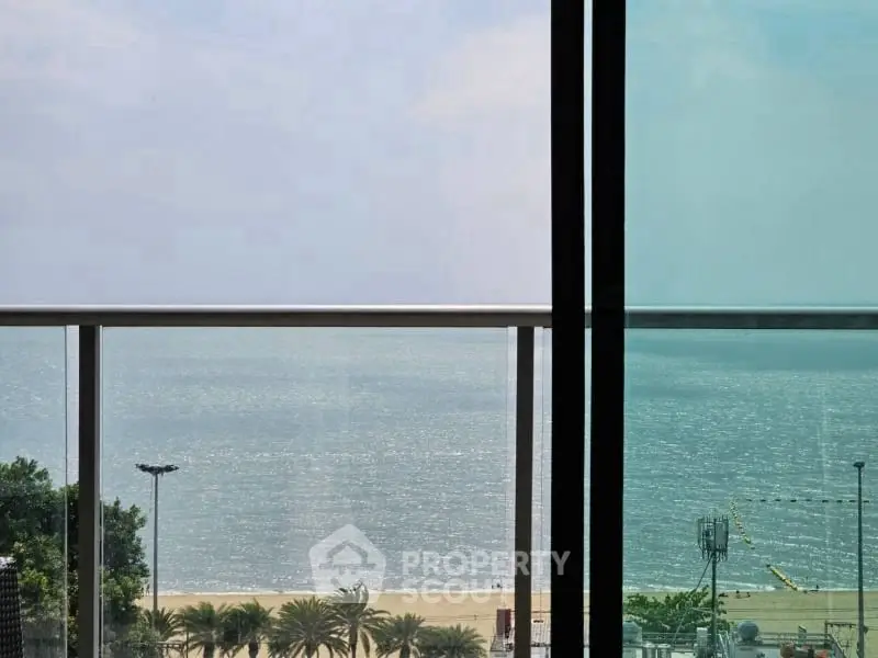 Stunning beachfront view from a modern balcony with glass railing, perfect for relaxation and enjoying the ocean breeze.