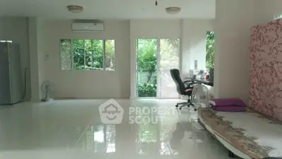 Spacious living area with large windows and greenery view, featuring a desk and bed setup.