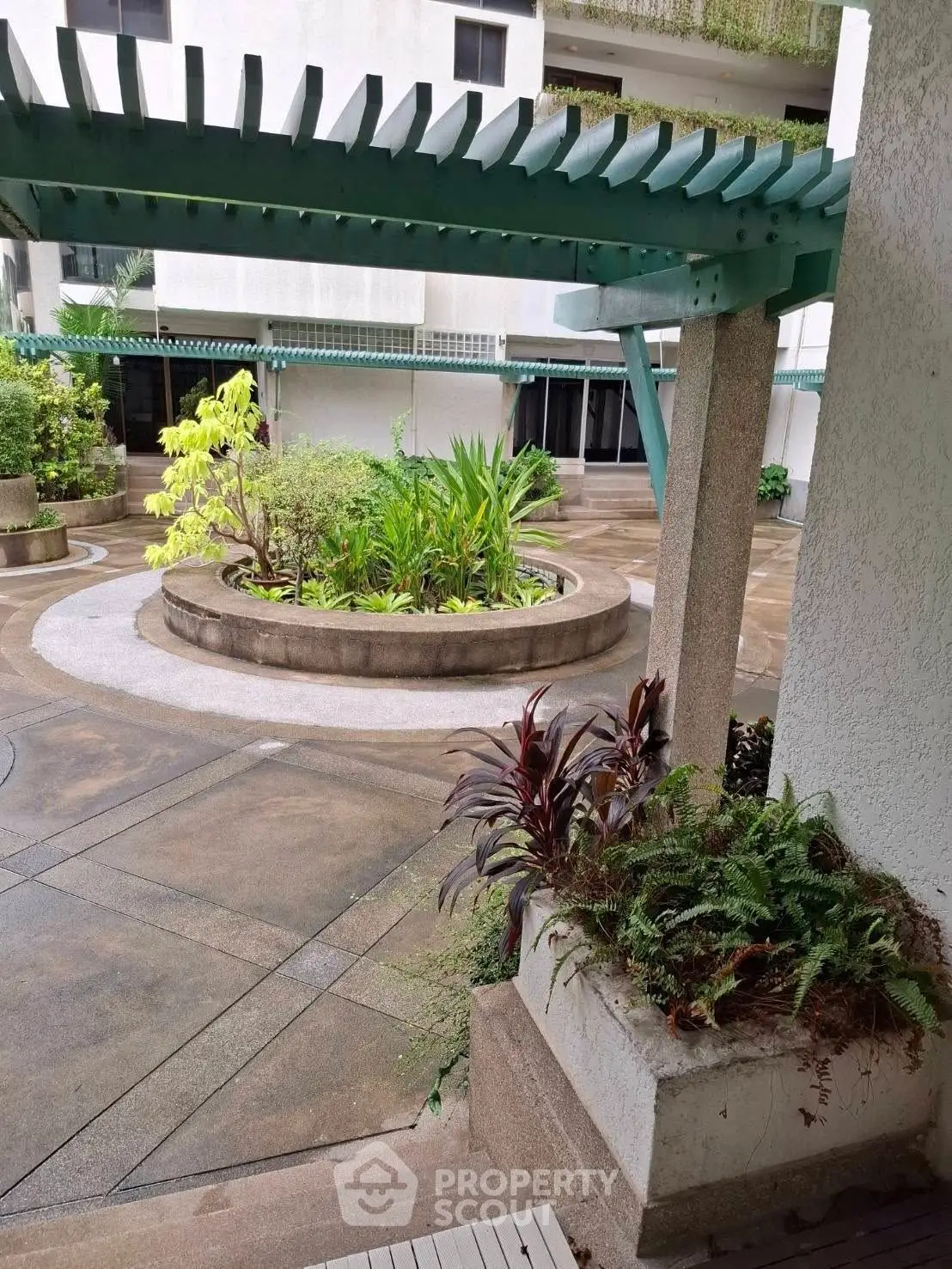 Charming courtyard with lush greenery in a modern residential complex, offering a serene outdoor retreat.