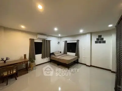 Spacious bedroom with modern decor and ample natural light, featuring a cozy bed and stylish furniture.