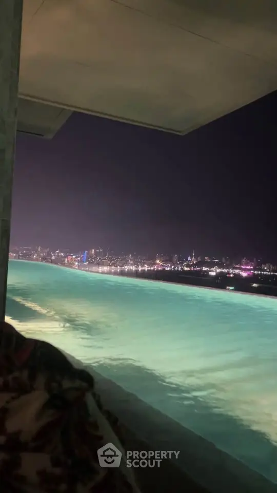 Stunning night view from an infinity pool overlooking a vibrant city skyline.