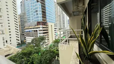 Urban balcony view with modern high-rise buildings and lush greenery