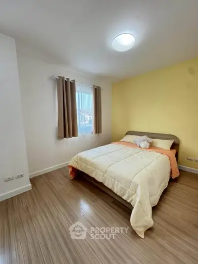 Cozy bedroom with warm yellow accent wall and natural light