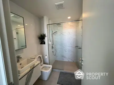 Modern bathroom with glass shower and sleek fixtures in contemporary home.