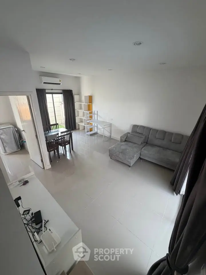 Spacious living room with modern gray sofa and dining area, perfect for family gatherings.