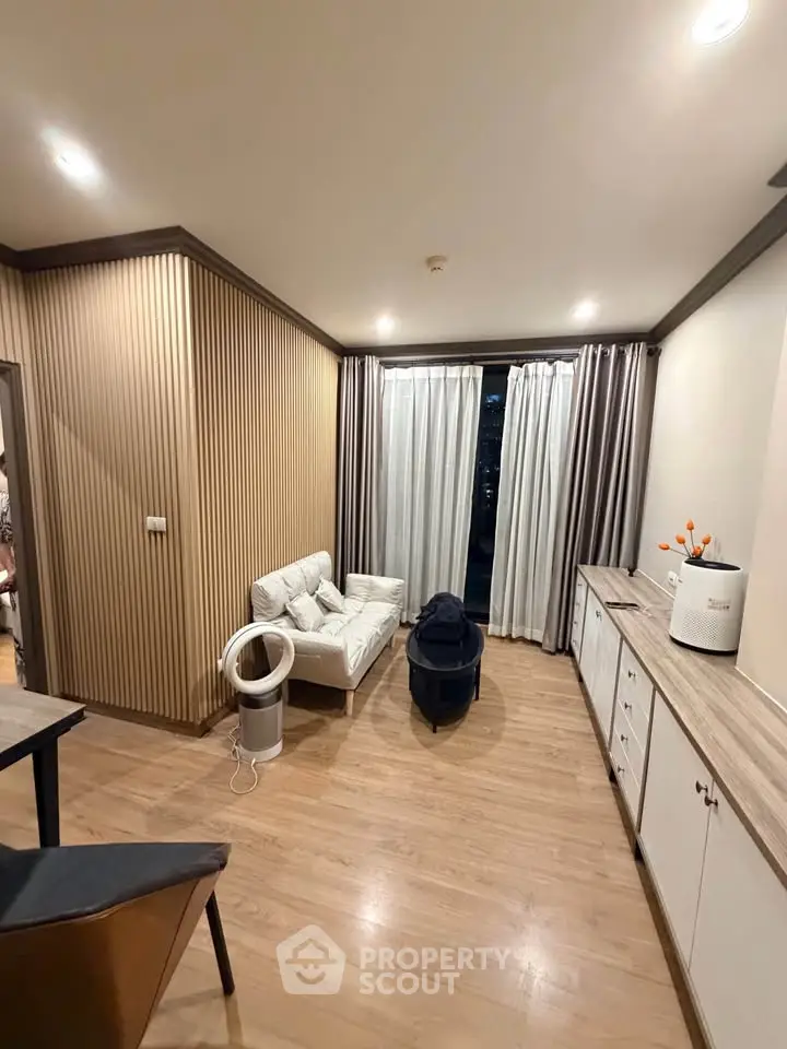 Modern living room with stylish decor and wooden flooring, featuring cozy seating and elegant curtains.