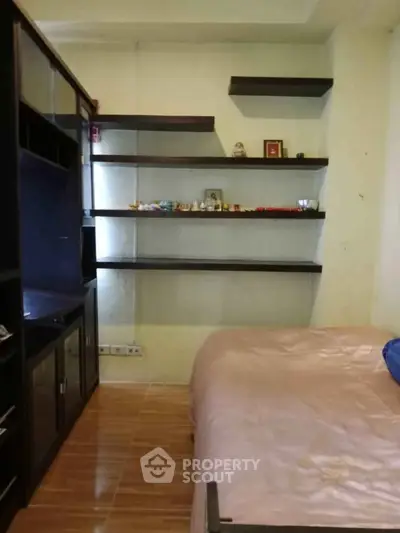 Cozy bedroom with built-in shelves and wooden flooring, perfect for a compact living space.
