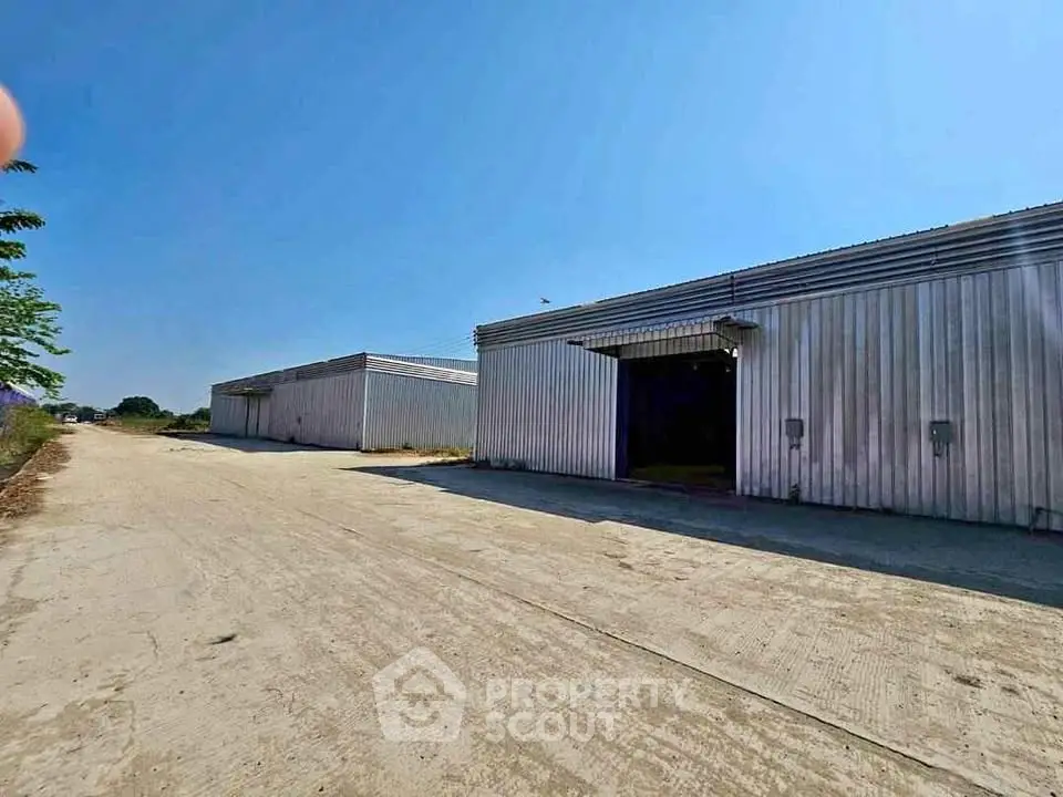 Spacious industrial warehouse with large open area and clear blue sky.