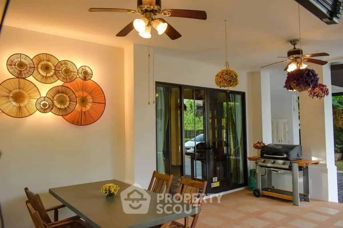 Charming outdoor dining area with ceiling fans and decorative wall art, perfect for entertaining.