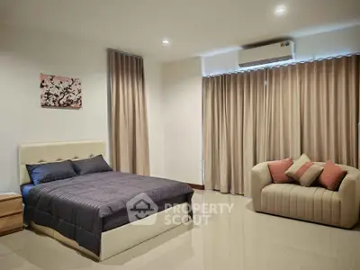 Spacious bedroom with modern decor and cozy seating area, perfect for relaxation.