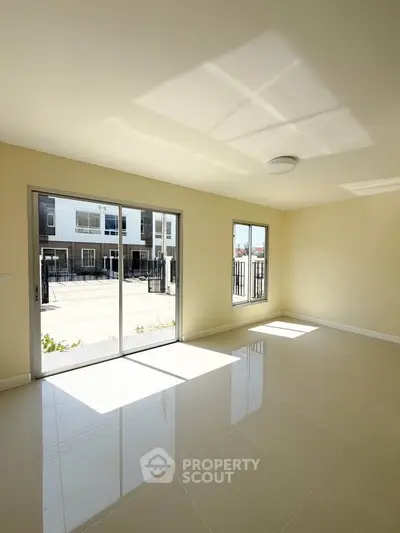 Bright and spacious living room with large windows and glossy tiled floors, offering a modern and inviting atmosphere.