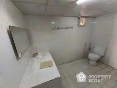 Spacious bathroom with tiled walls and floor, featuring a sink and toilet.