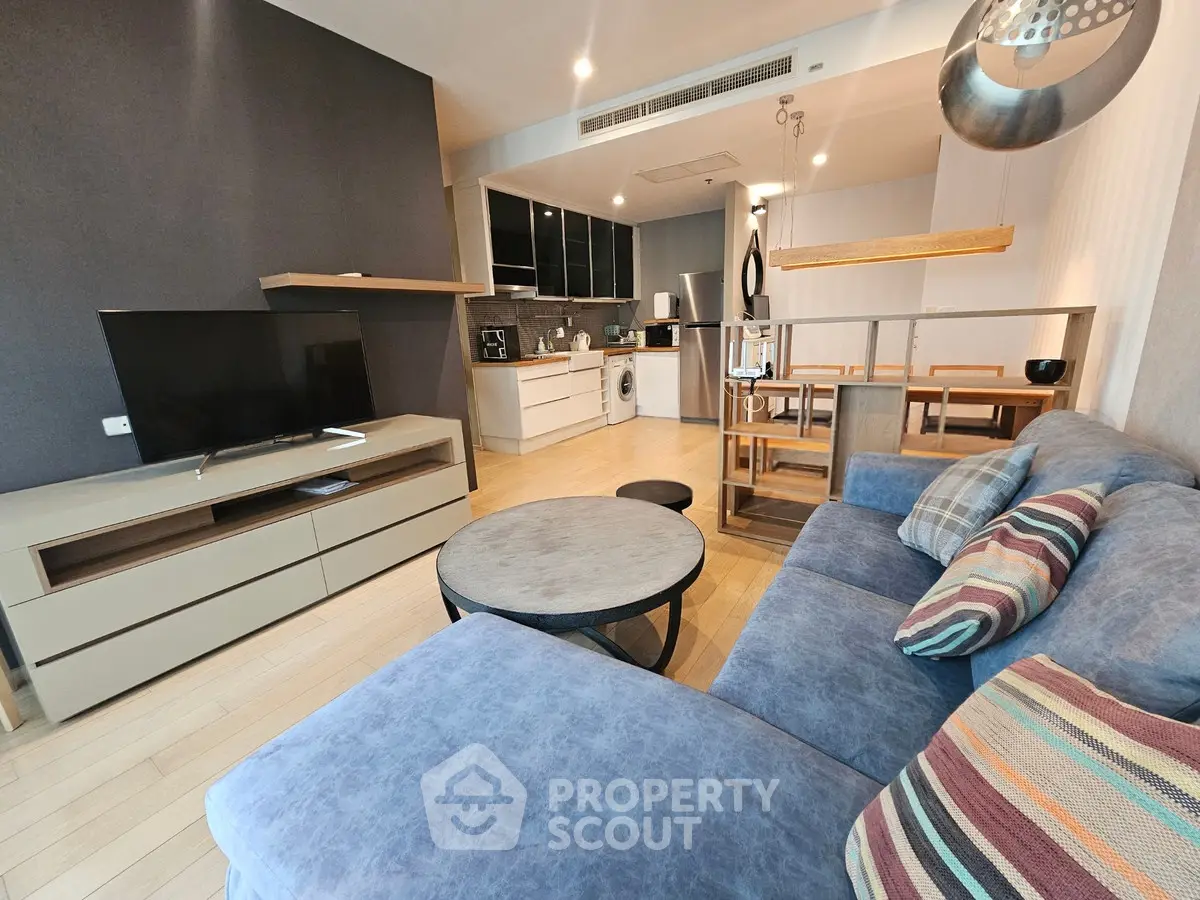 Modern living room with open kitchen, stylish decor, and cozy seating area