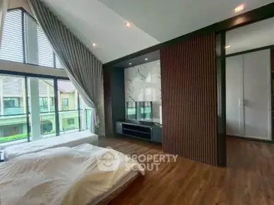Luxurious bedroom with high ceilings and large windows offering a serene view, perfect for relaxation.