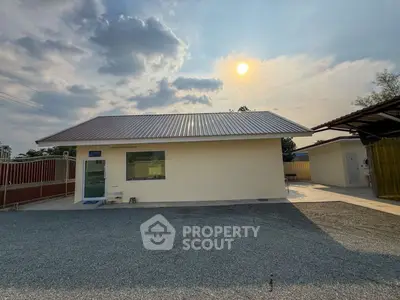 Charming single-story home with metal roof and spacious driveway under a bright sky.