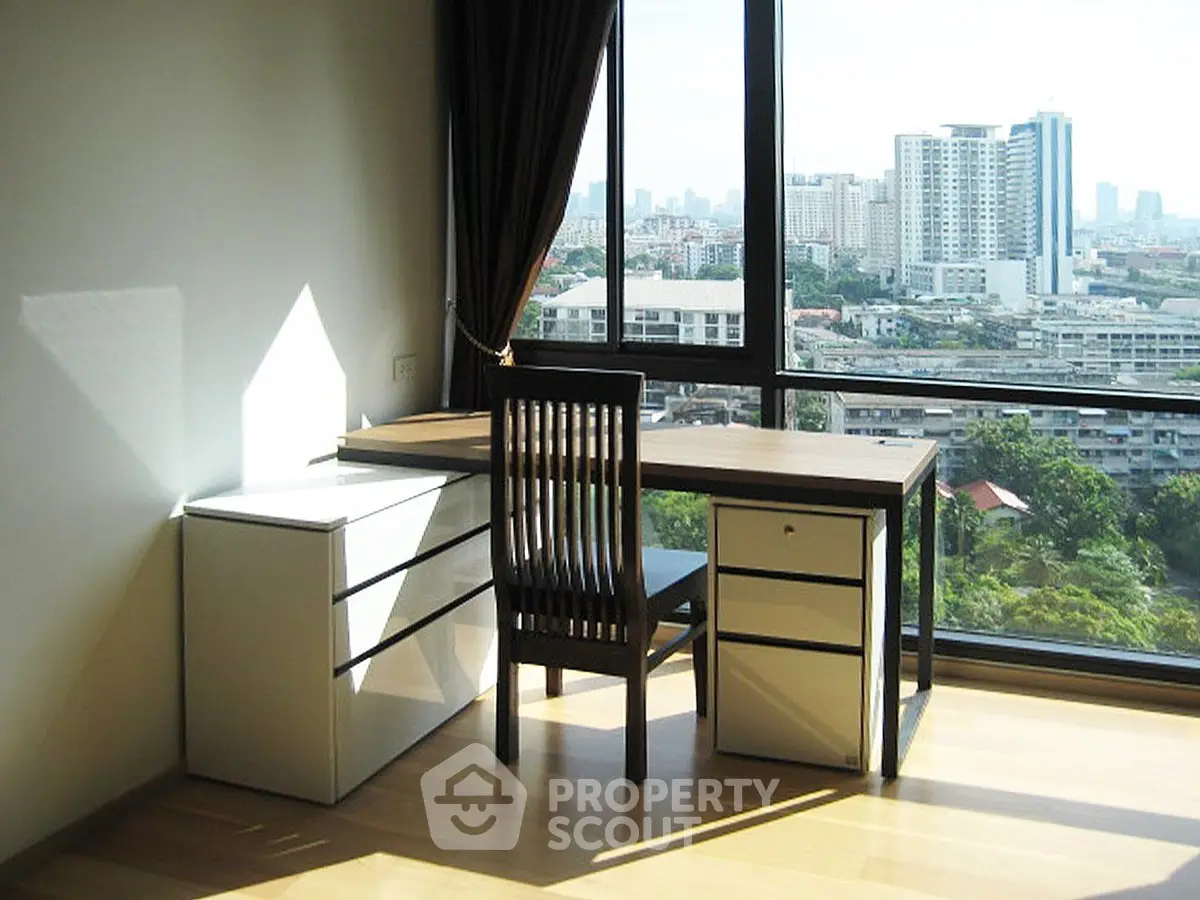 Bright study room with city view, modern desk and chair, large windows.