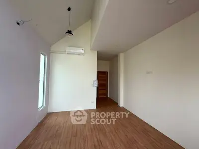 Spacious empty room with wooden flooring and high ceiling