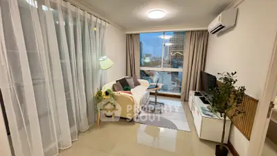 Cozy living room with modern decor and city view, featuring a comfortable sofa and stylish lighting.