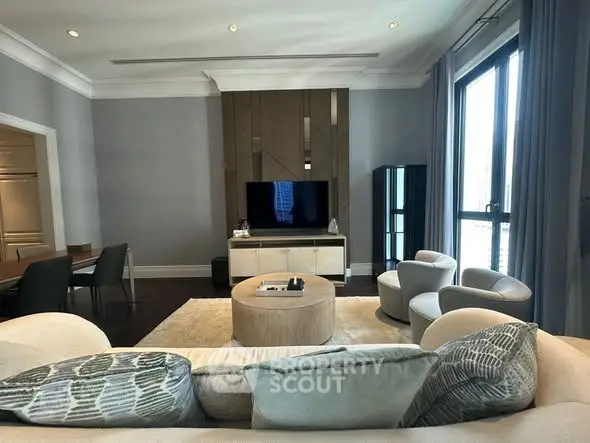 Luxurious modern living room with elegant furniture and large windows offering natural light.