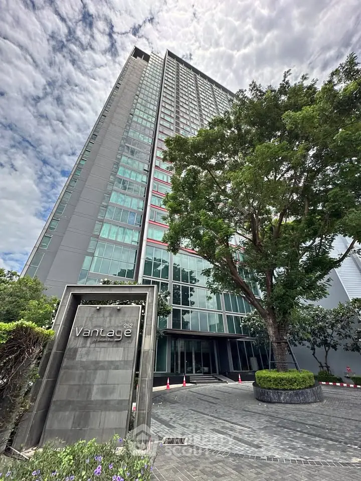 Stunning high-rise building with modern architecture and lush greenery at the entrance, perfect for urban living.