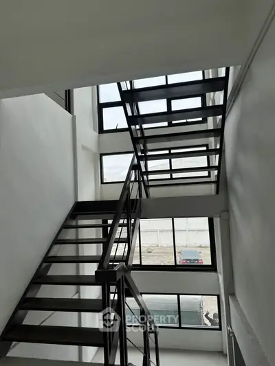 Modern industrial staircase with large windows and natural light