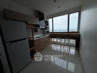 Modern kitchen with city view, featuring sleek cabinetry and bar seating by large windows.