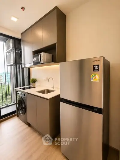 Modern kitchen with sleek appliances and balcony view in a stylish apartment.