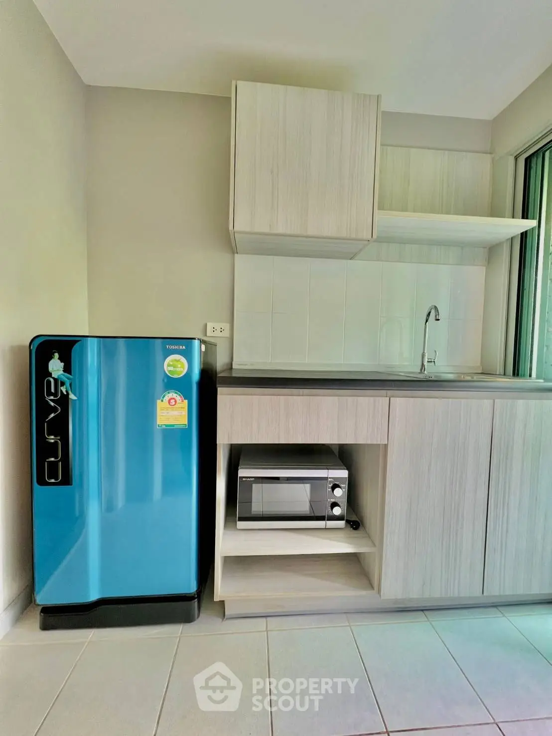 Modern kitchen with sleek blue fridge and microwave in stylish apartment.