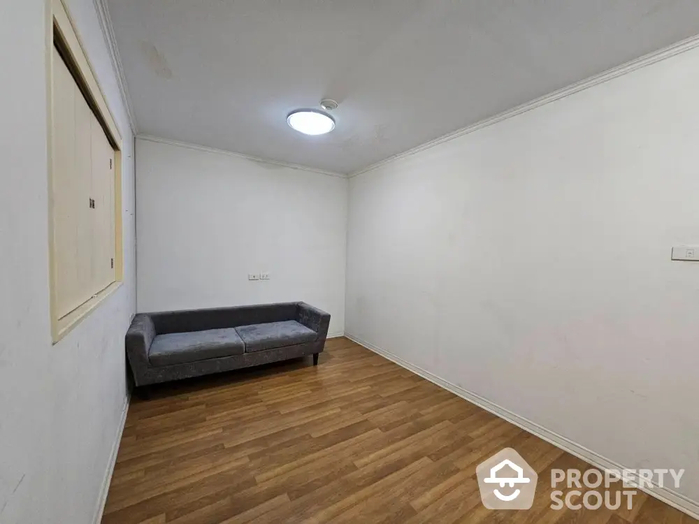 Minimalist room with wooden flooring and a gray sofa, perfect for a cozy living space.