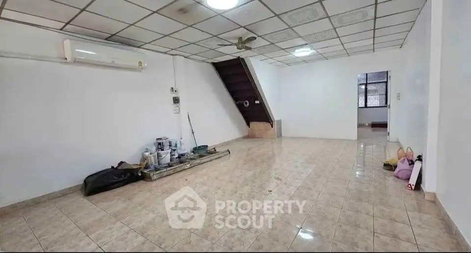 Spacious tiled living room with staircase and air conditioning, ideal for customization.