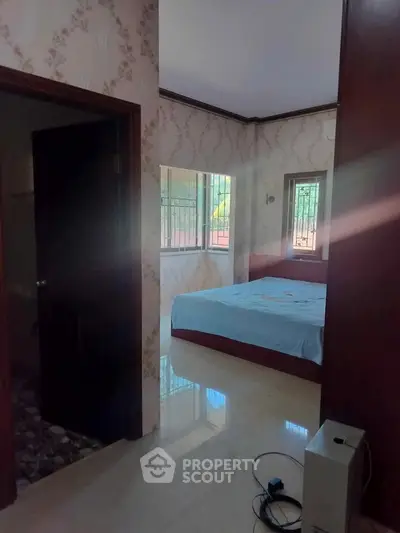 Cozy bedroom with natural light and elegant wallpaper, featuring a comfortable bed and serene ambiance.
