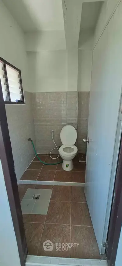 Compact bathroom with tiled walls and floor, featuring a toilet and shower area.