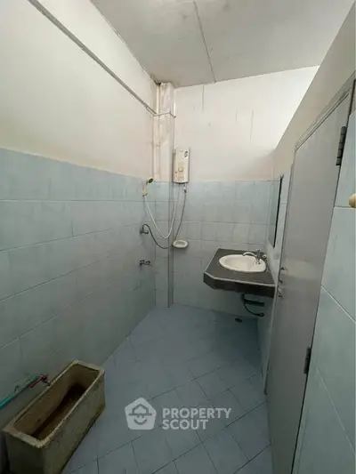 Compact bathroom with tiled walls and basic fixtures, ideal for small spaces.