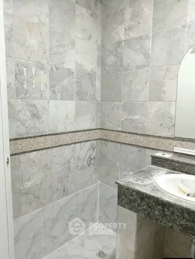 Elegant marble bathroom with modern sink and shower area, perfect for luxury living.