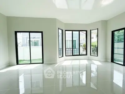 Spacious modern living room with large windows and glossy tiled floors, offering abundant natural light.