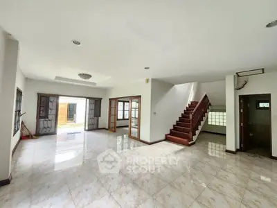 Spacious open-plan living room with elegant staircase and marble flooring