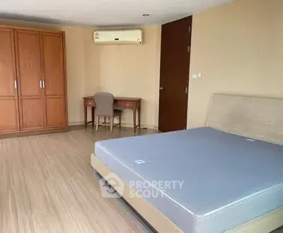 Spacious bedroom with wooden flooring, large wardrobe, and study desk.