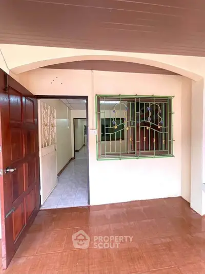 Charming entrance with wooden door and tiled floor, leading to a cozy interior space.