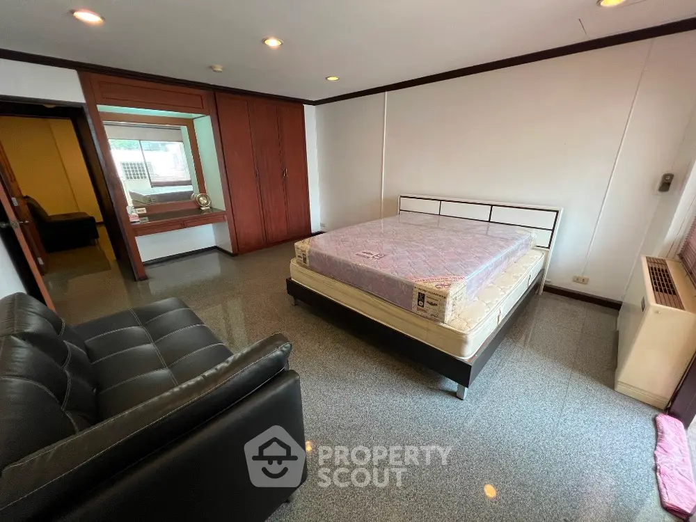 Spacious bedroom with modern furnishings and large window for natural light