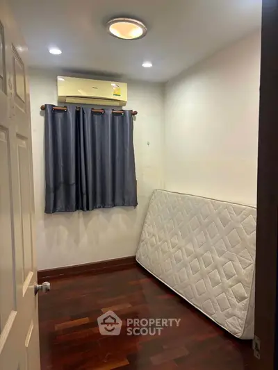 Cozy small bedroom with wooden flooring and air conditioning, perfect for minimalist living.