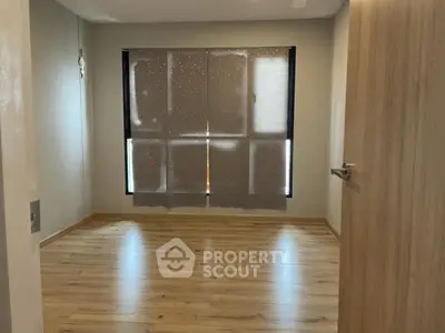 Spacious empty bedroom with wooden flooring and large window