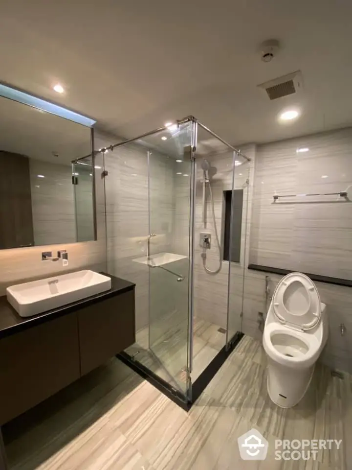 Modern bathroom with glass shower and sleek fixtures in luxury apartment