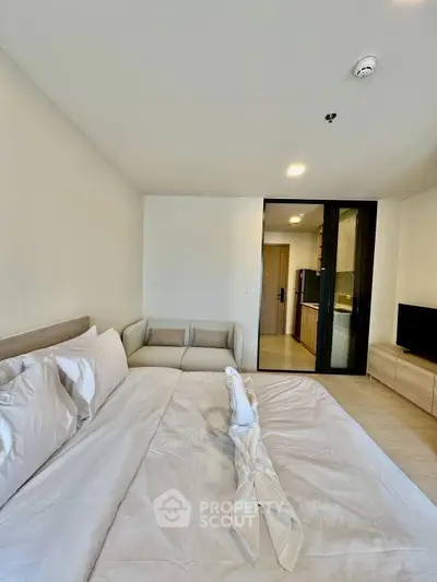 Modern bedroom with cozy sofa and open kitchen layout in stylish apartment