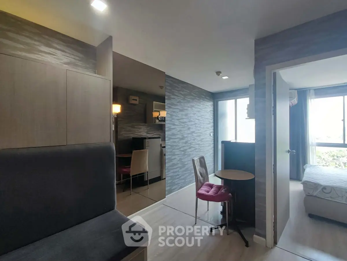 Modern apartment interior with open layout, featuring a cozy living area and a glimpse of the bedroom.