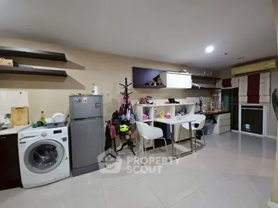 Modern kitchen with washing machine and dining area in open layout apartment.