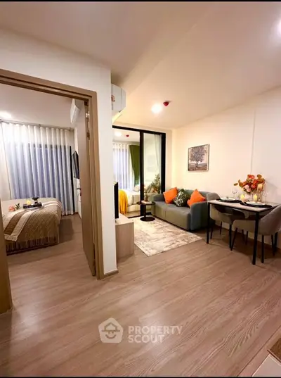 Modern open-plan living room with cozy seating and dining area, adjacent to a stylish bedroom.