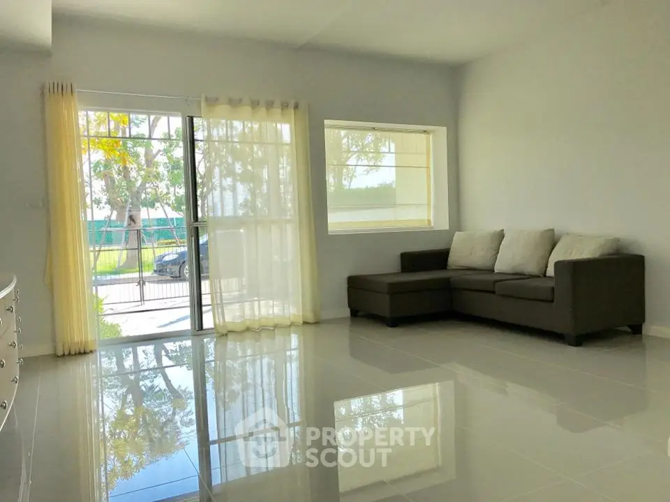 Spacious living room with modern sofa and large windows offering natural light.