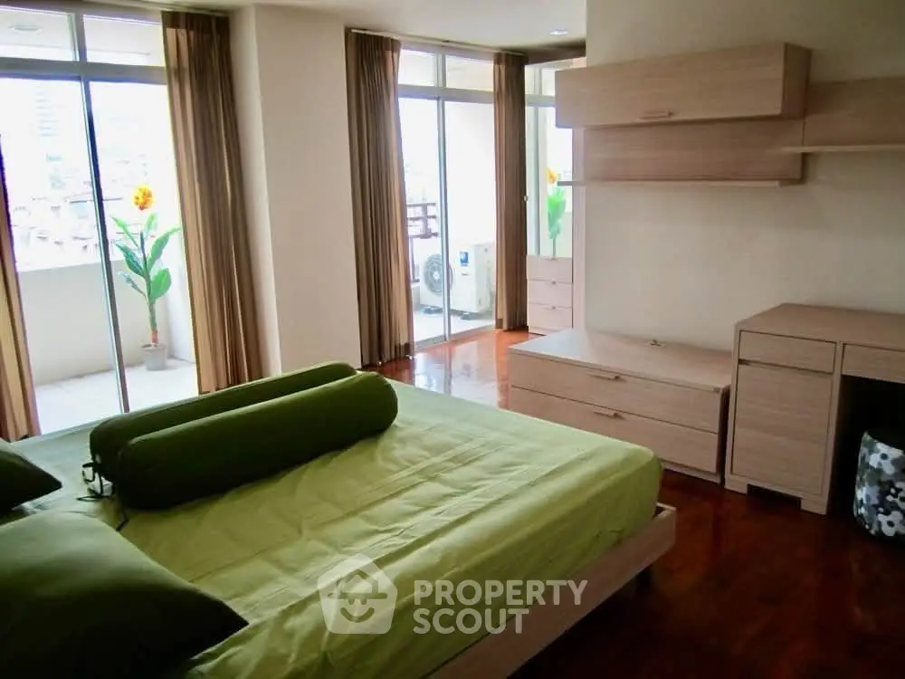 Spacious bedroom with balcony access and modern furnishings in a bright apartment.