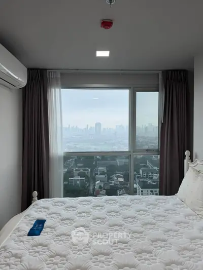 Cozy bedroom with city view, featuring a comfortable bed and large window for natural light.