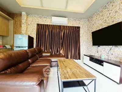 Modern living room with leather sofa, wall-mounted TV, and stylish stone accent wall.